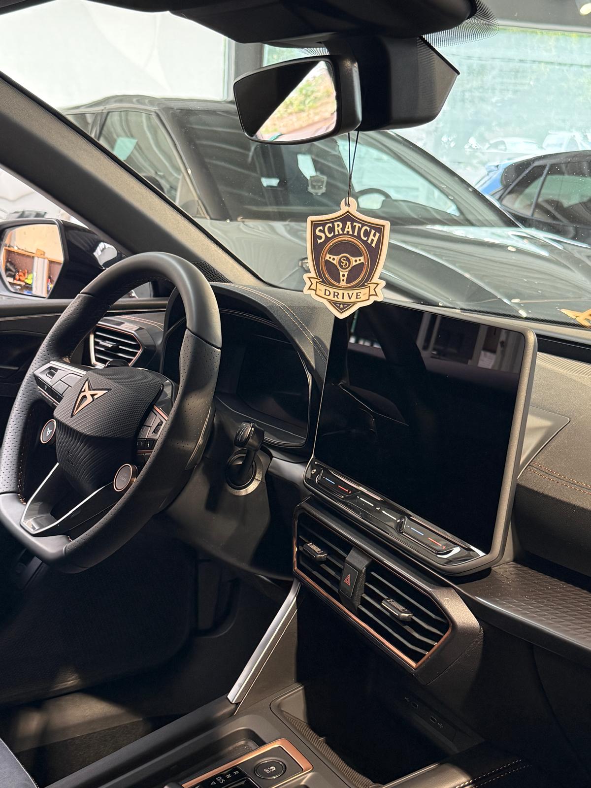Nahaufnahme des Scratch & Drive Metall-Badges am Rückspiegel im Auto